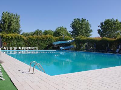 Piscina all'aperto con scivolo, sedie a sdraio e ombrelloni.