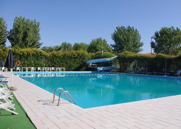 Piscina all'aperto con scivolo, sedie a sdraio e ombrelloni.