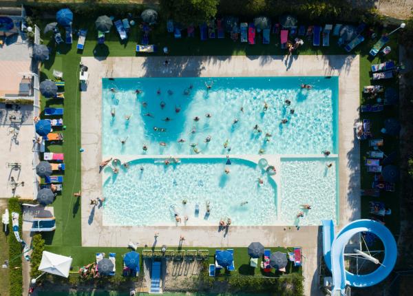Vista aerea di una piscina affollata con scivolo d'acqua.