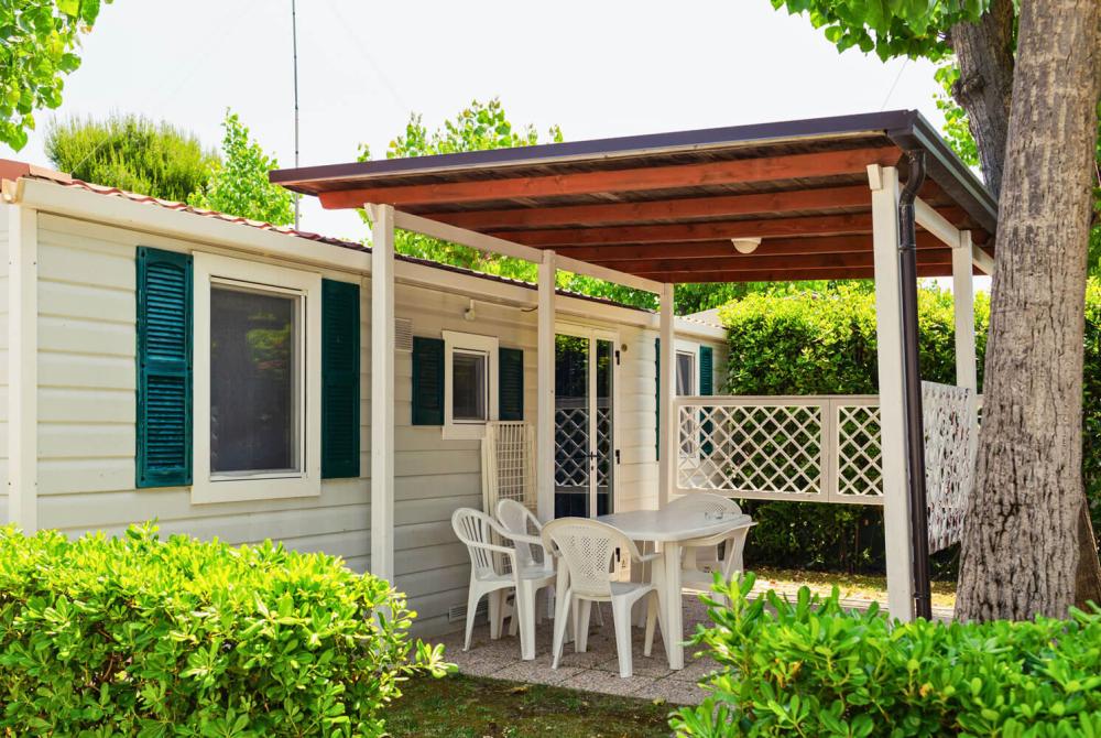 Mobile home with porch and chairs in the garden.